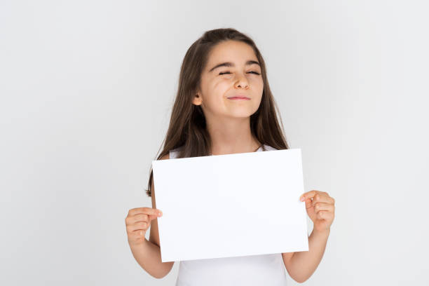 istock Child girl smiling holding white sheet blank isolated 1212064314