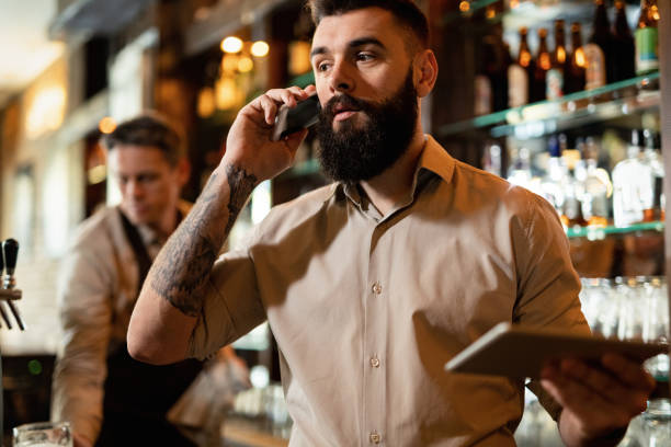 istock Young barista talking on the phone while working in a bar. 1212065368