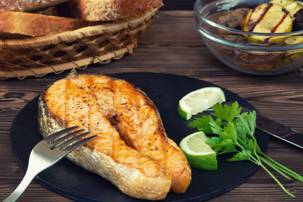istock Grilled salmon steak on a black slate dish with parsley and lime 1212065574