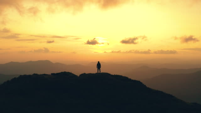 The man standing on a mountain against the sunrise