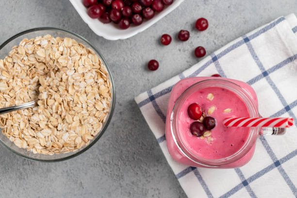 čerstvě domácí smoothie s brusinkami, ovesnými vločkami a jogurtem v hrnečku na šedém stole. koncept zdravého stravování. pohled shora, plochá - jogurt fotky - stock snímky, obrázky a fotky