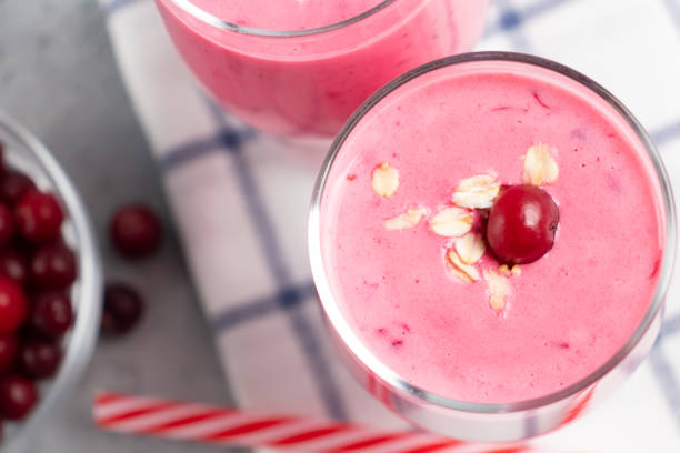 dvě sklenice s čerstvě domácím smoothie jogurtu, ovesných vlčích a brusinek na šedém stole. koncept zdravého stravování - jogurt fotky - stock snímky, obrázky a fotky