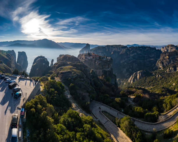 vista aérea do mosteiro trinity e fotos de tirar o fôlego do vale e do cânion histórico de meteora ao pôr do sol, kalambaka, grécia, sombras, estrada torcida, ponte, montanhas como colunas - meteora monk monastery greece - fotografias e filmes do acervo