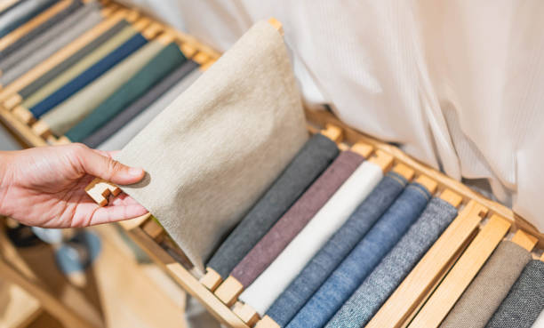 The girl's hand is choosing the roll of fabric and textile.  The roll of fabric are the earth-tone cone. stock photo
