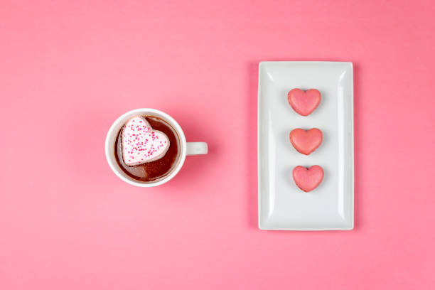 Top view of hot cocoa with heart shaped marshmallow and pink heart shaped macaroons