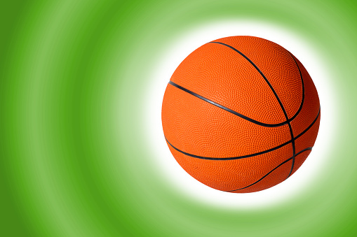 Basketball on a green color gradient background. Space for copy.
