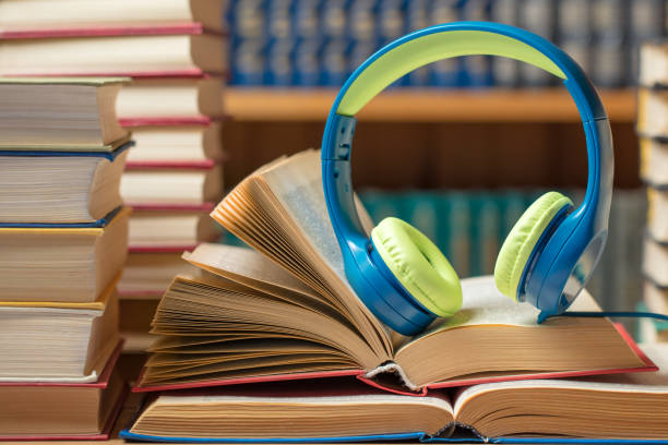 istock Audio book concept - headphones with books at the library 1212073214