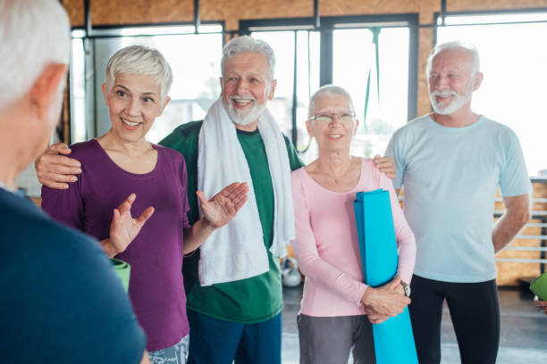 一緒にヨガをする前に楽しくリラックスしている高齢者のグループ - health club social gathering exercising sport ストックフォトと画像