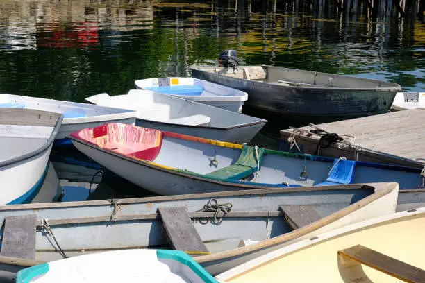 Docked small rowboats and skiffs tied together on a calm and peaceful Coastal Maine dock and Harbor