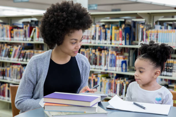 istock Mother and daughter sitting at table in library 1212076246