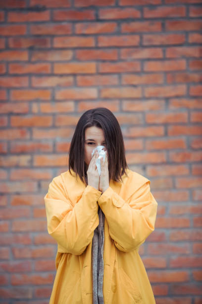istock Sick young woman blowing her nose 1212076680