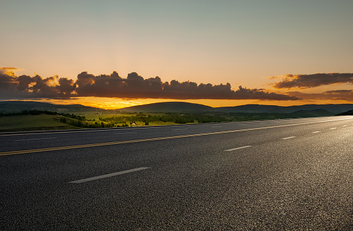 The endless grassland in spring and the forest hills in the distance beside the asphalt highway