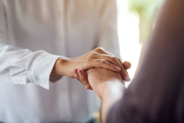 istock Women holding each other hands for comfort 1212091283