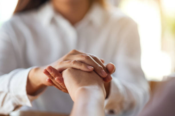 istock Women holding each other hands for comfort 1212091332