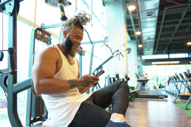 istock Latino man in gym exercise machine is browsing his cell phone 1212093484