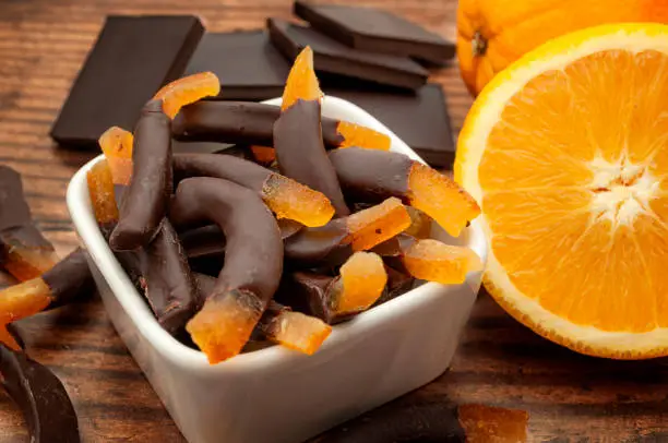 Seasonal candies and sweets, citrus fruit dipped in chocolate and homemade sweet treat concept with close up on candied orange peel, raw oranges and chocolates