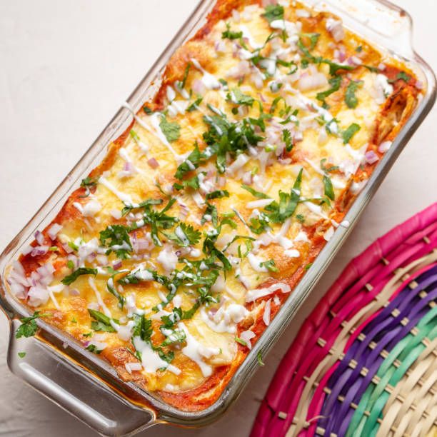 istock Mexican red baked enchiladas with melted cheese and sour cream on white background 1212104882