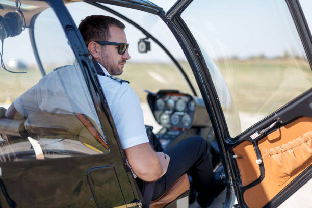 istock Pilot in uniform sitting in helicopter cockpit with door open 1212112639