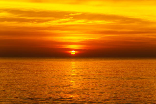 istock sunset with large yellow sun under the sea surface 1212114354