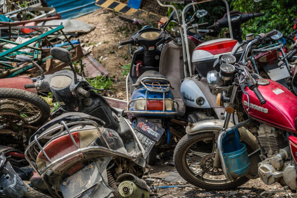 Yangshuo, China - August 2019 : Used, old, damaged and disposed of motorbikes, motorcycles and scooters piled up in the yard outside metal recycling plant in Yangshuo, Guangxi Province