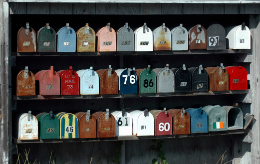 An array of mailboxes in various colors and condition by a side road in Massachusetts