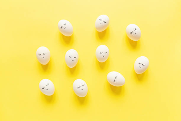istock Creative easter eggs with cute face and sleepy eyes on pastel yellow background. Happy Easter concept. Flat lay, top view, mockup, template, overhead, copy space 1212118992