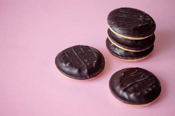 A pile of Jaffa cakes A pile of Jaffa cakes. Cookies covered with dark chocolate and filled with pink strawberry or cherry marmalade. Delicious biscuits isolated on pink background with copyspace Jaffa Cake stock pictures, royalty-free photos & images