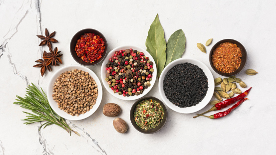 Culinary background: overhead view of herbs and Indian spices arranged at the left of black background leaving useful copy space for text and/or logo at the left. High resolution 42Mp studio digital capture taken with Sony A7rII and Sony FE 90mm f2.8 macro G OSS lens