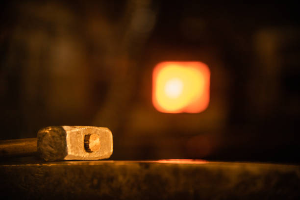 Glowing hammer on the anvil in dark lighting in the workshop. Mid shot