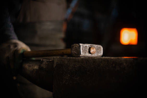 istock A hammer on the anvil in workshop - a man worker standing on the background 1212134772