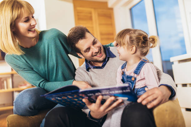 istock Happy family reading book at home, having fun. 1212135786