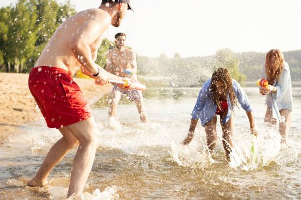 istock Happy people with water guns have fun on the beach 1212135889