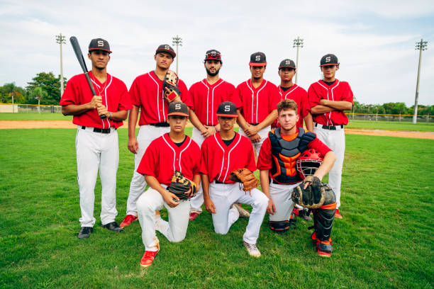 Outdoor group portrait of young Hispanic baseball team Portrait of teenage Hispanic baseball teammates suited up and standing outdoors with bat and gloves. baseball diamond photos stock pictures, royalty-free photos & images