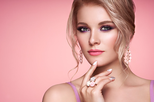 Portrait Beautiful Blonde Woman with Jewelry. Model Girl with Pearl Manicure on Nails. Elegant Hairstyle. Precious Stones and Silver. Beauty and Fashion Accessories. Perfect Make-Up. Pink Background