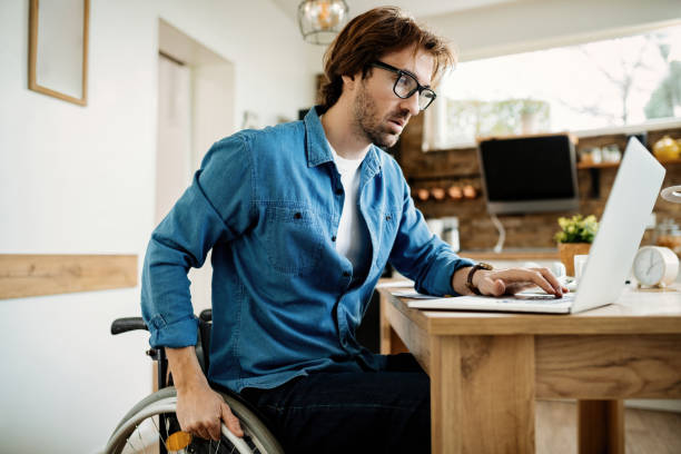 istock Young entrepreneur in wheelchair working on a computer at home. 1212139062