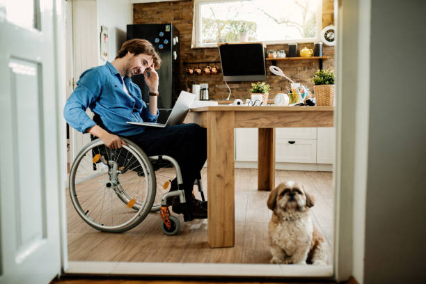istock Happy disabled freelance worker using laptop while being with his dog at home. 1212139643
