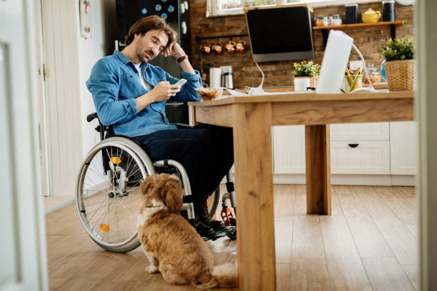 istock Smiling freelance worker in wheelchair using phone while having lunch break at home. 1212140108