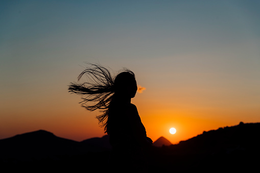 Girl with hair flying in breeze enjoying sunset over rural landscape, nature, dusk, sunset