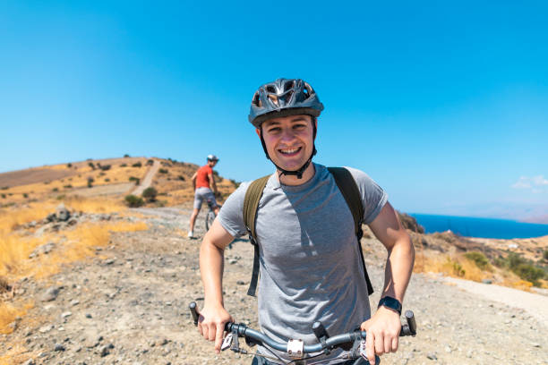istock Man wearing helmet smiling at camera on cycle ride 1212146363