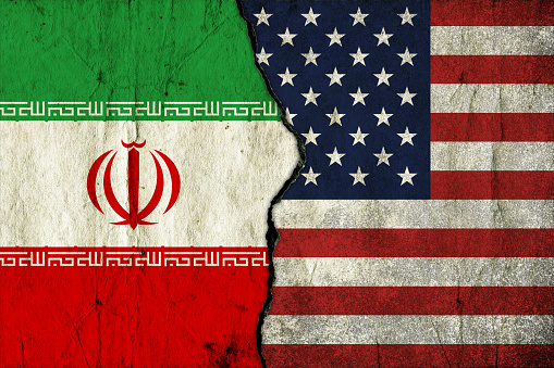 Flags of USA and Iran painted on cracked wall background