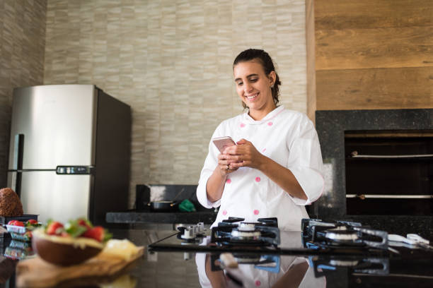 chef woman using smartphone in kitchen - egg cell imagens e fotografias de stock