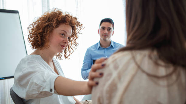 Addicted people comforting woman at psychotherapy session Addicted people comforting woman at psychotherapy session. Support gesture. Woman comforting woman patient at group rehub meeting. Rear view at upset woman feel depression get psychological support hand on shoulder stock pictures, royalty-free photos & images