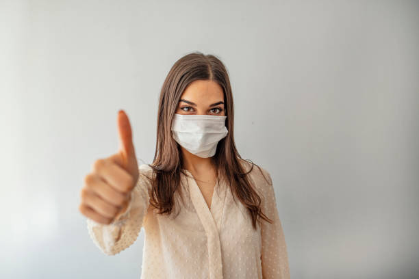 istock Woman with protective mask showing thumb up, and looking at camera 1212152872