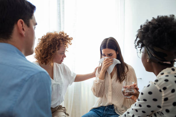 Emotional woman sharing her story during support session. Emotional woman sharing her story during support session. Distraught woman during counseling session. Young woman with his head in his hands is upset during a therapy session. woman comforting depressed friend stock pictures, royalty-free photos & images