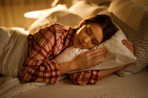 Mujer durmiendo en la cama abrazando suave almohada blanca photo