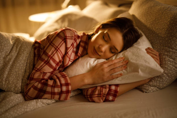 Woman sleeping in bed hugging soft white pillow stock photo