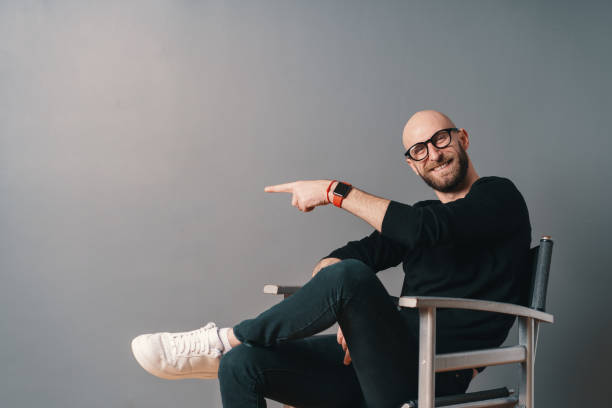 istock Modern young man pointing with finger on gray copy space 1212161728