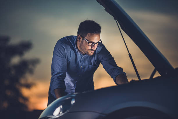 istock Young man repairing his broken car in the evening. 1212164065