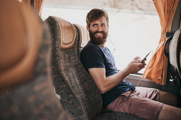 The bus is way less crowded Shot of a handsome young man using his cellphone while sitting on the bus travel destinations 20s adult adventure stock pictures, royalty-free photos & images