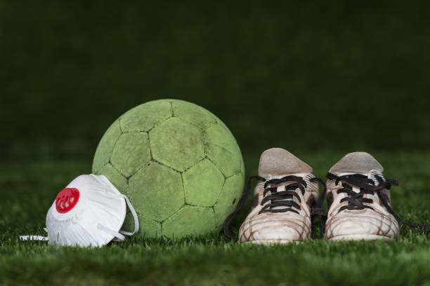 Coronavirus in sport The soccer ball and shoes with face mask as a symbol coronavirus international team soccer photos stock pictures, royalty-free photos & images